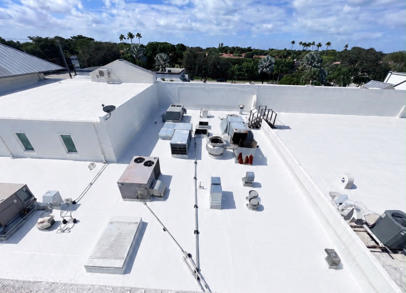 After — A commercial roof carrying rooftop HVAC, ducting and equipment stands. The coating is carried up the parapets and detailed around every curb.