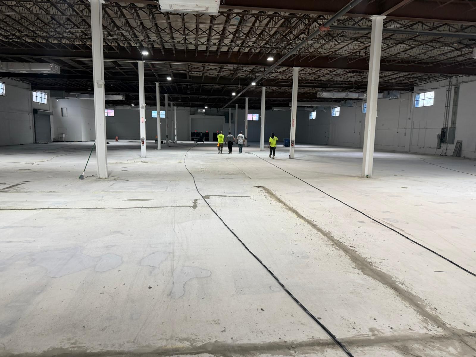 During — The same warehouse floor part-way through and completed — ground back, densified and burnished between the standing columns.